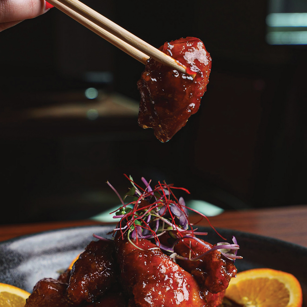 chopsticks holding food above a plate of food